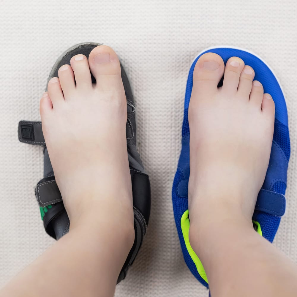 A picture of a child's feet on top of different pairs of shoes.