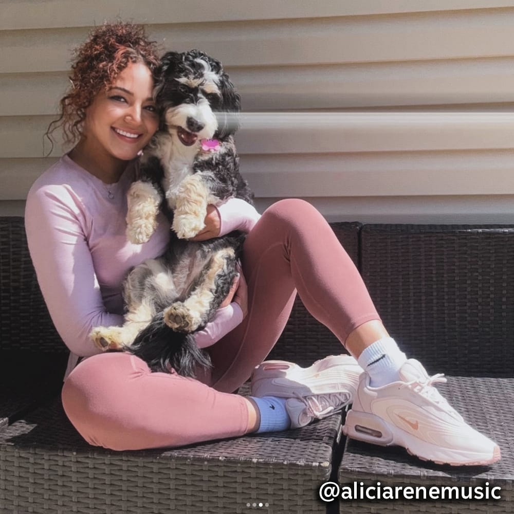 A woman sitting outside holding a dog @aliciarenemusic. Super Shoes on Instagram.