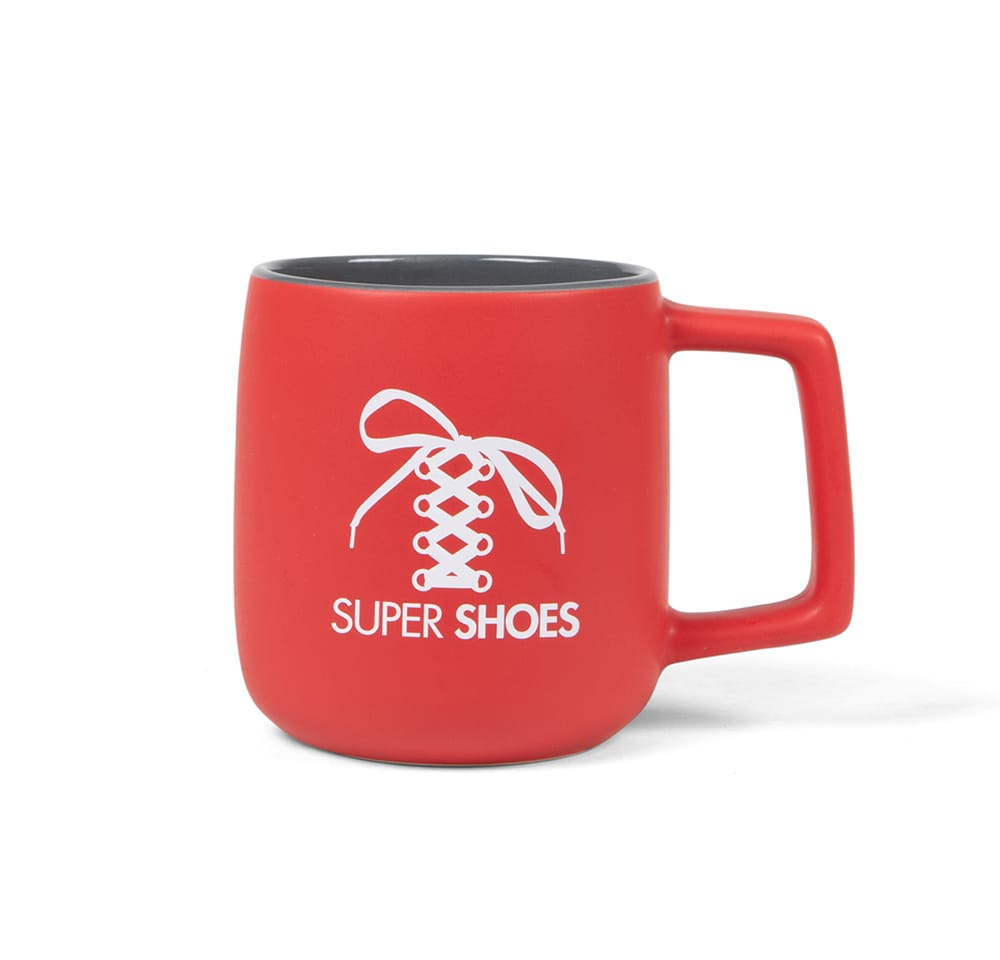 Red coffee mug with a white Super Shoes logo.