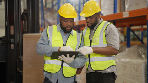Two men in a warehouse looking at a tablet.